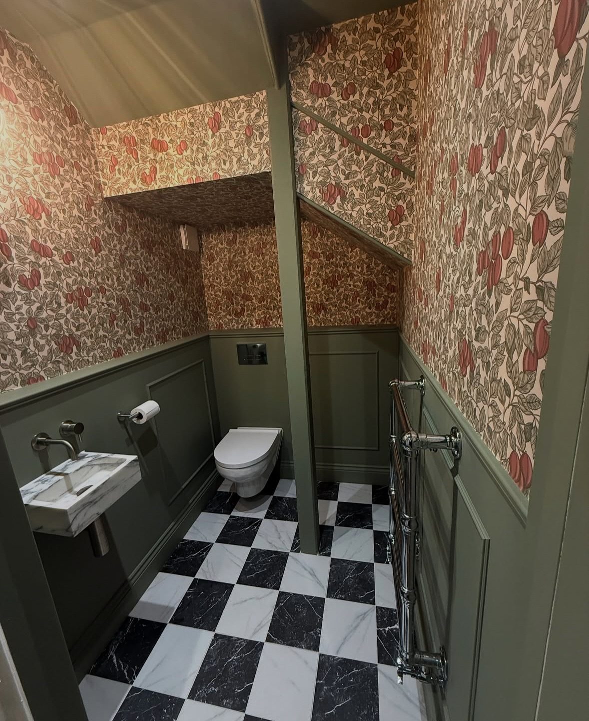 Cloakroom with green painted panelling, patterned walls and a black and white chequered floor